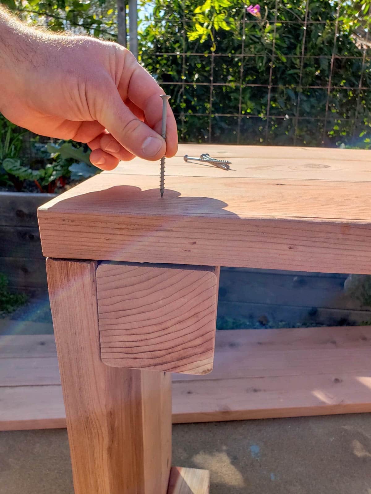 A screw is being held to a 2x6 board with a 4x4 corner piece below the board.