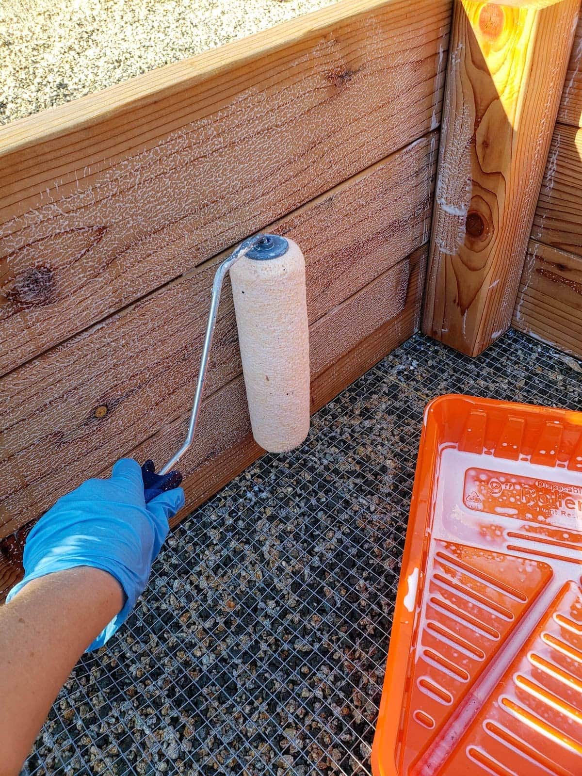 The inside of a finished bed is being sealed using a paint roller to apply the garden sealant.