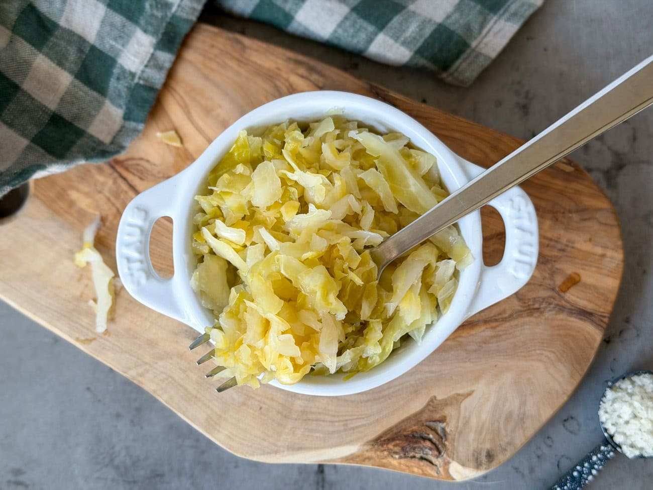 A small white ramekin filled with sauerkraut, a fork rests in the ramekin with a portion of kraut sitting on the fork.