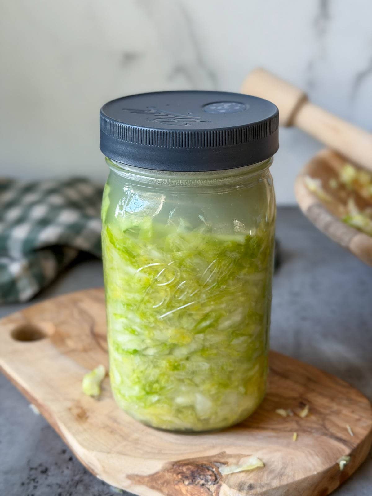 A quart mason jar is two thirds of the way full of cabbage with two inches of brine above the top most portion of cabbage.
