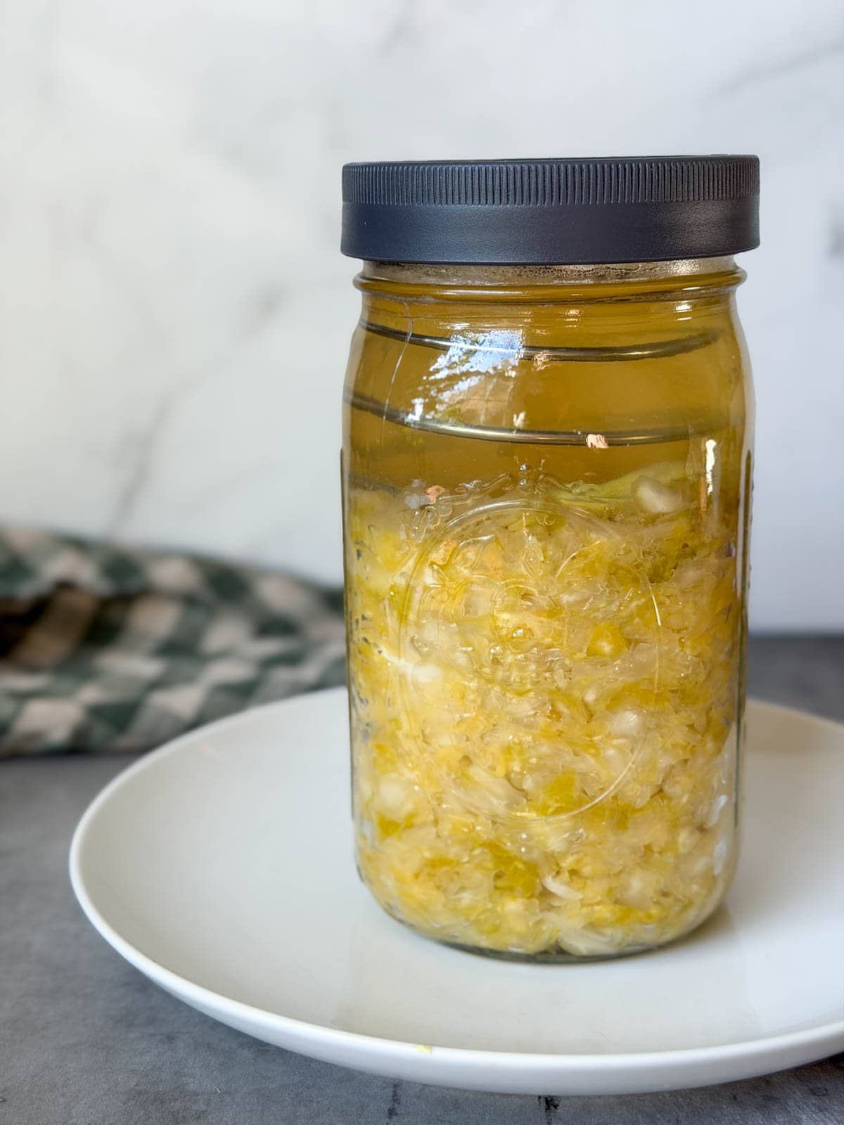 A quart mason jar with a fermentation lid is two thirds full of sauerkraut.