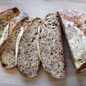a sliced loaf of sourdough zucchini bread splayed out on a cutting board
