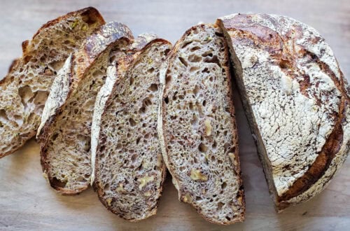 a sliced loaf of sourdough zucchini bread splayed out on a cutting board