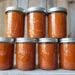 Two rows of pint mason jars stacked atop one another with four jars on the bottom and three jars on top full of roasted tomato sauce.