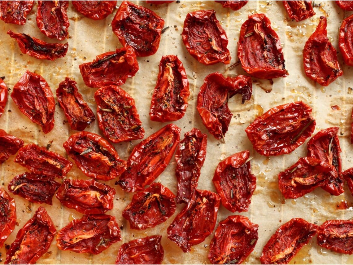 Sun-dried tomatoes are scattered about on a dehydrator rack.