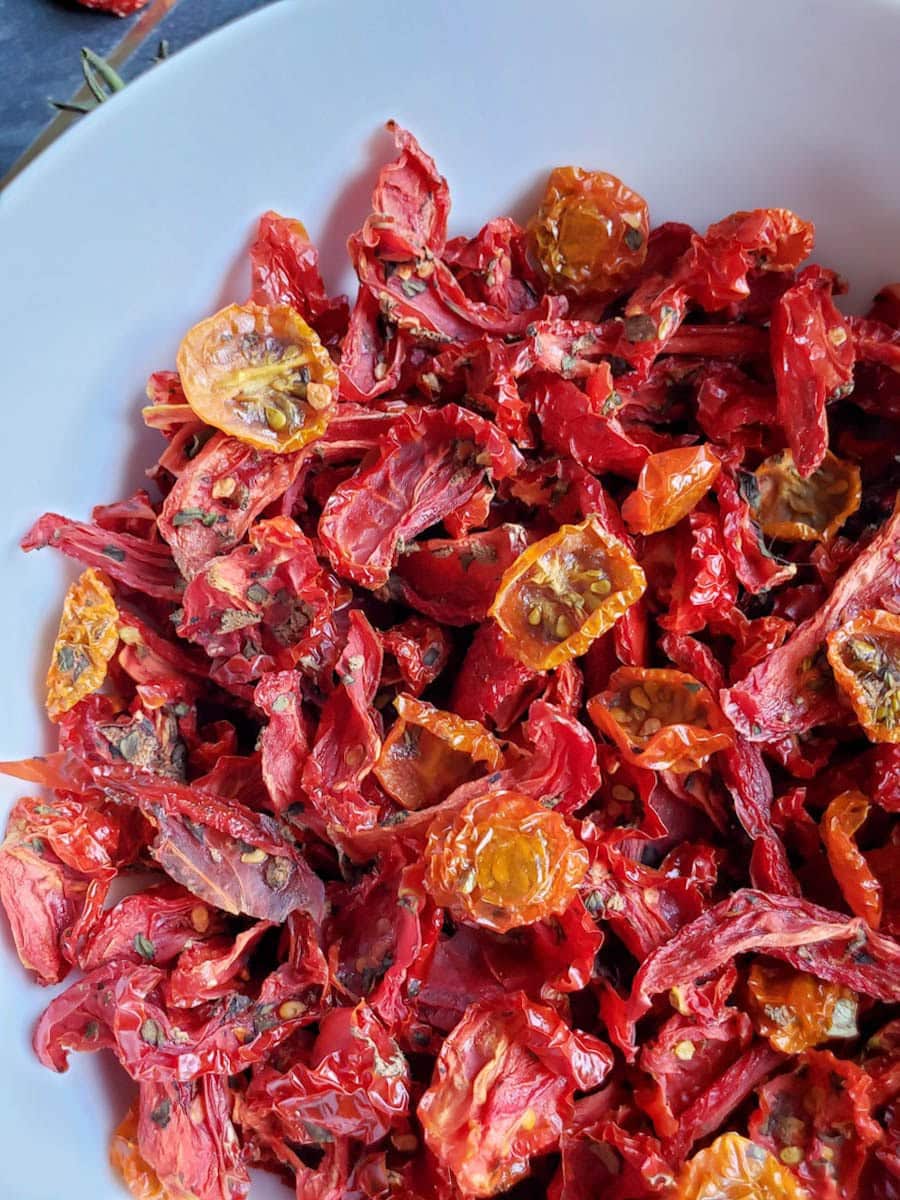 A white ceramic bowl is full of sun-dried tomatoes.