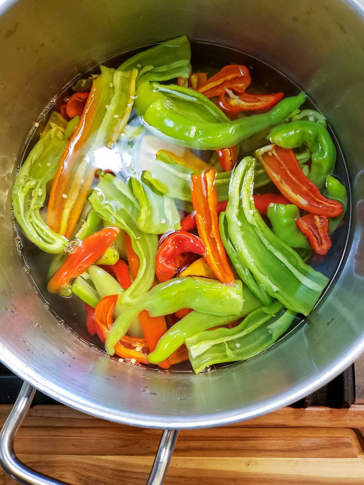 sliced chilis in a large pot filled halfway with hot water to blanch the peppers