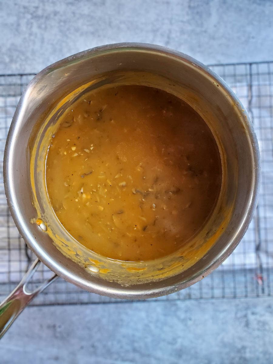 An overhead view of a cooking pot with finished vegan mushroom gravy, after the flour and red wine have been added and cooked to a thickened mixture.