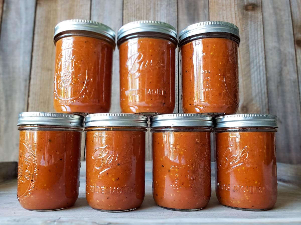 Seven pint sized mason jars full of roasted sauce stacked in a pyramid.