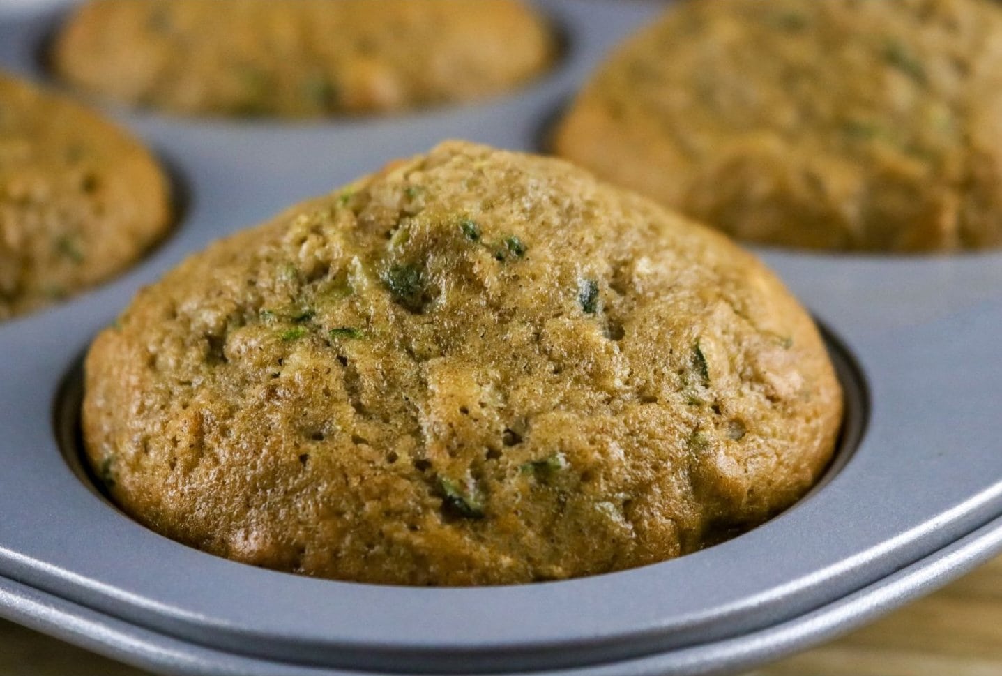A close up of a sourdough zucchini muffin, still in the baking pan