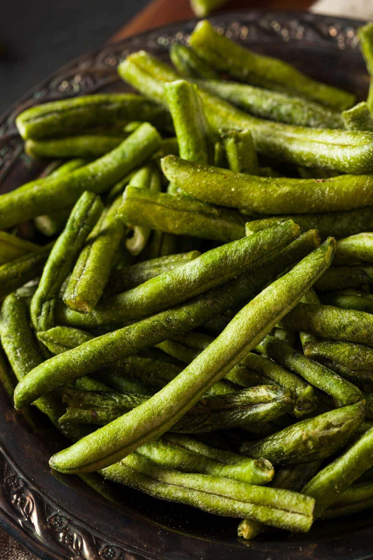 Dehydrated greens beans coated in a light seasoning are in a bowl.