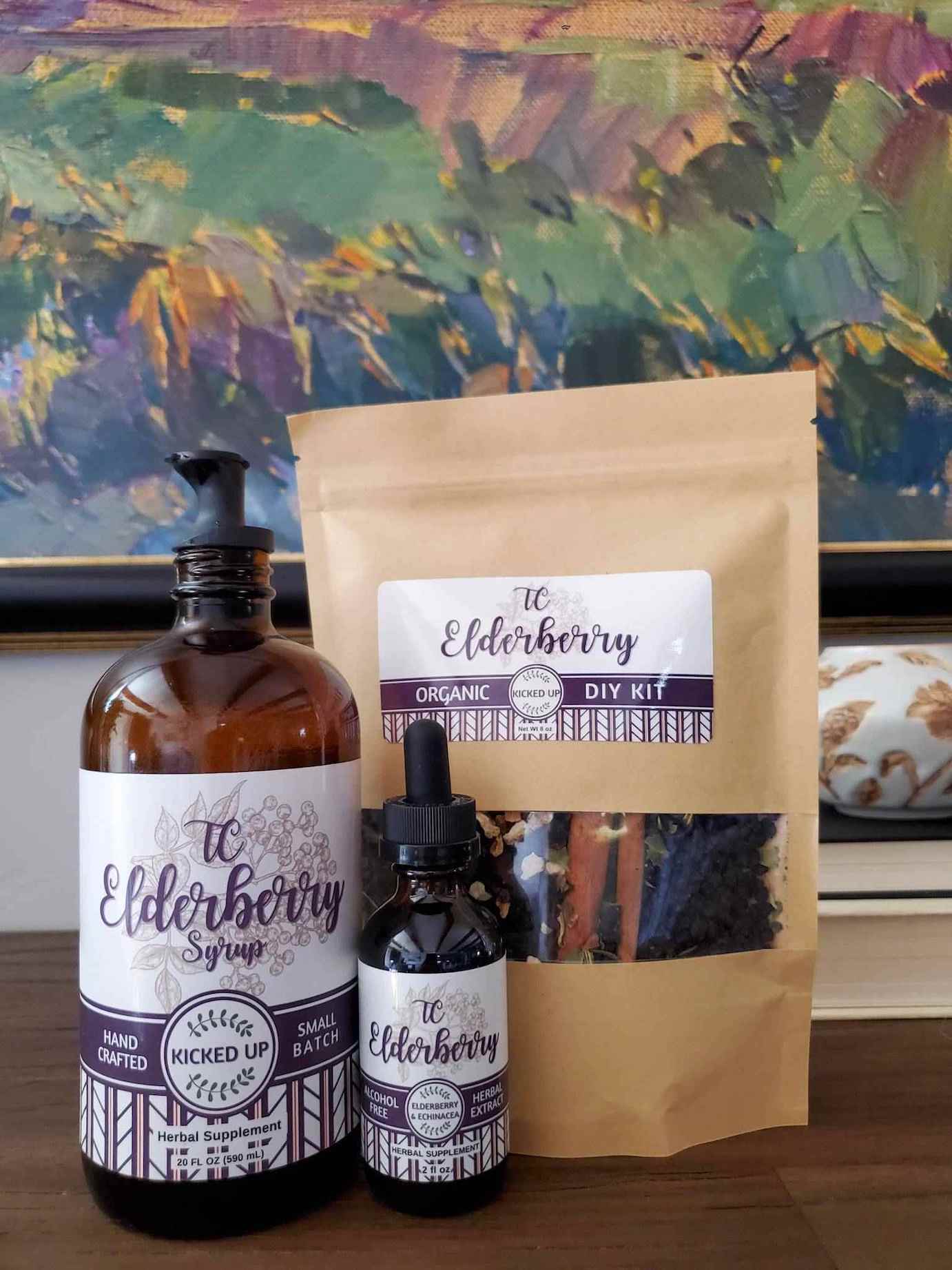 A jar of Elderberry syrup, elderberry herbal extract, and a DIY bag of dried elderberry syrup ingredients from TC Elderberry are on display..