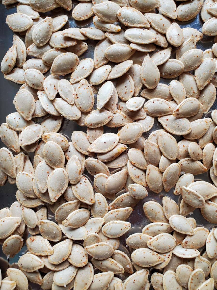 Raw pumpkin seeds are shown after soaking. They have been coated with coconut oil and sprinkled with salt and paprika.