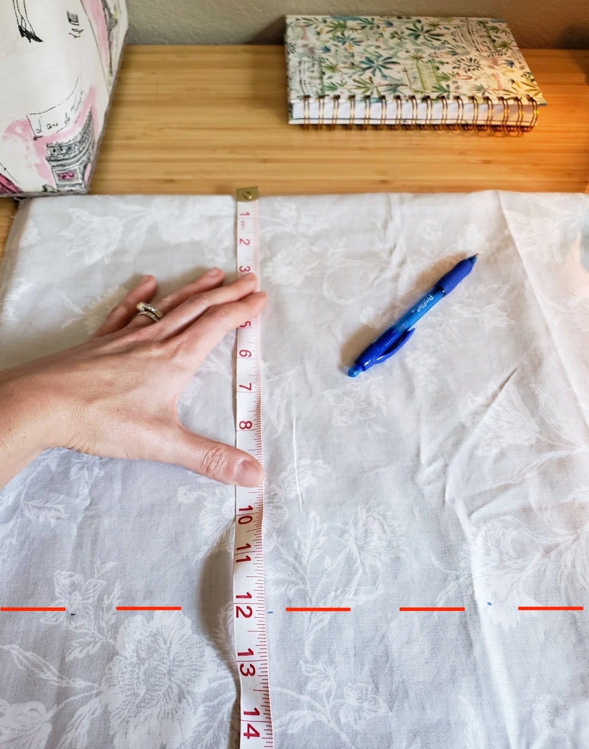 A close up of a hand measuring the DIY rice heating pad fabric, showing a dotted line at 12 inches where it will be cut