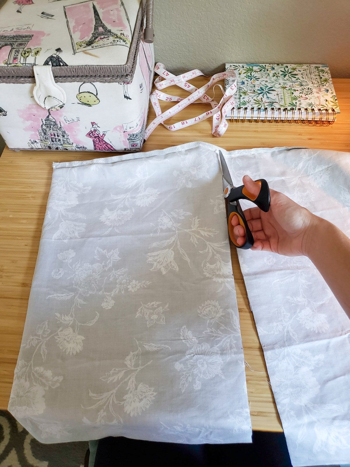 A hand holding scissors is cutting fabric to the correct size for the rice heating pad