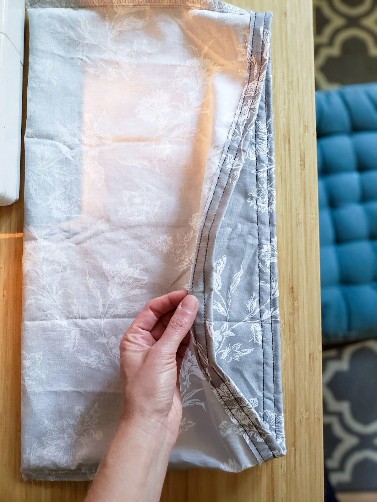 The empty rice heating pad fabric, now sewed and hemmed into a rectangular "envelope" shape, being held open by a hand to show the inside and stitches