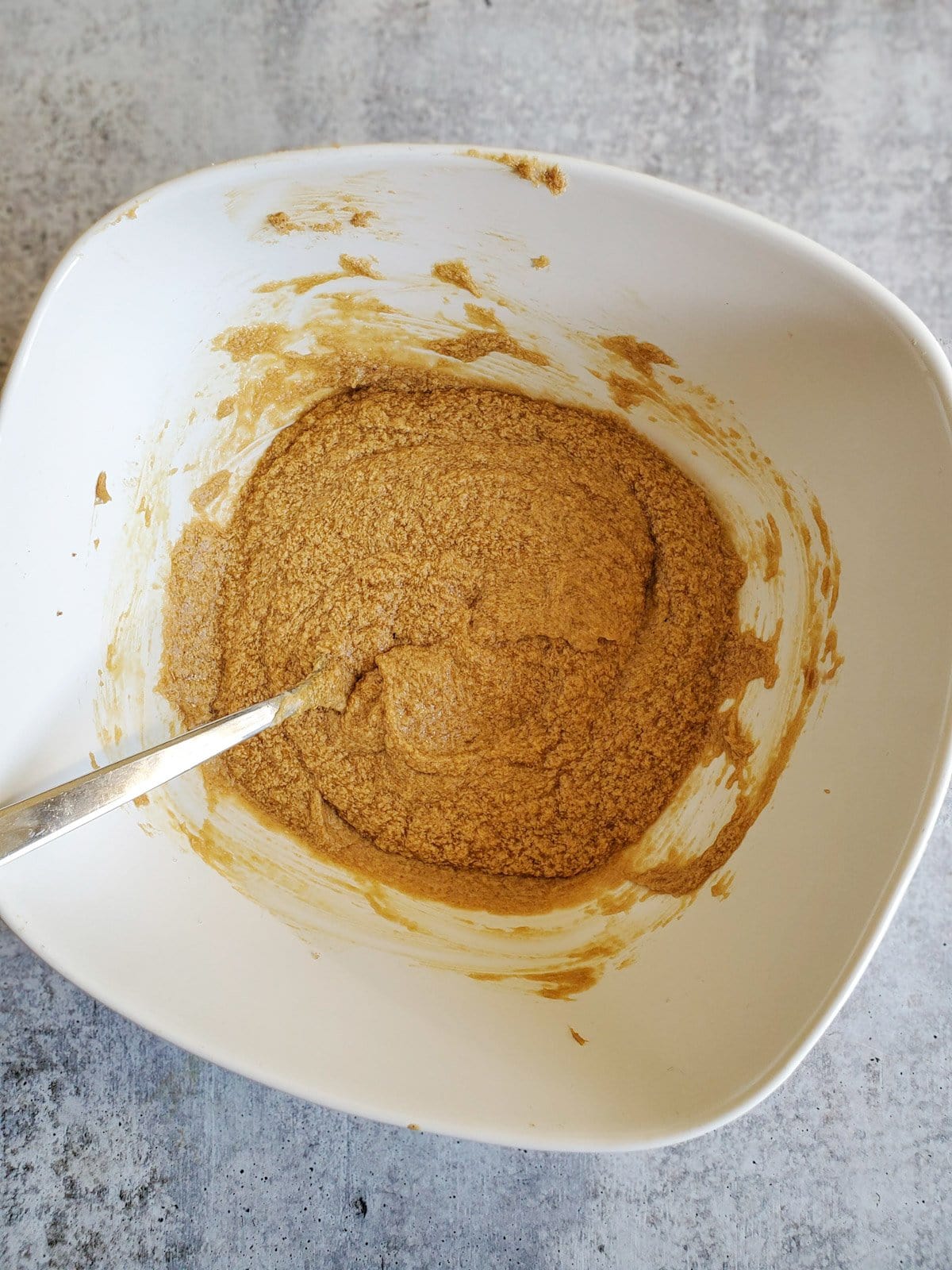 A top view of a white ceramic bowl with the wet cookie dough ingredients mixed together.