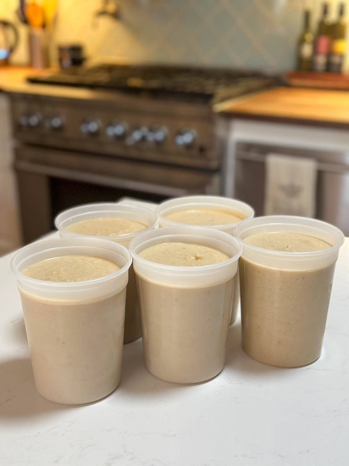 Five quart sized freezer safe containers full of roasted cauliflower soup.