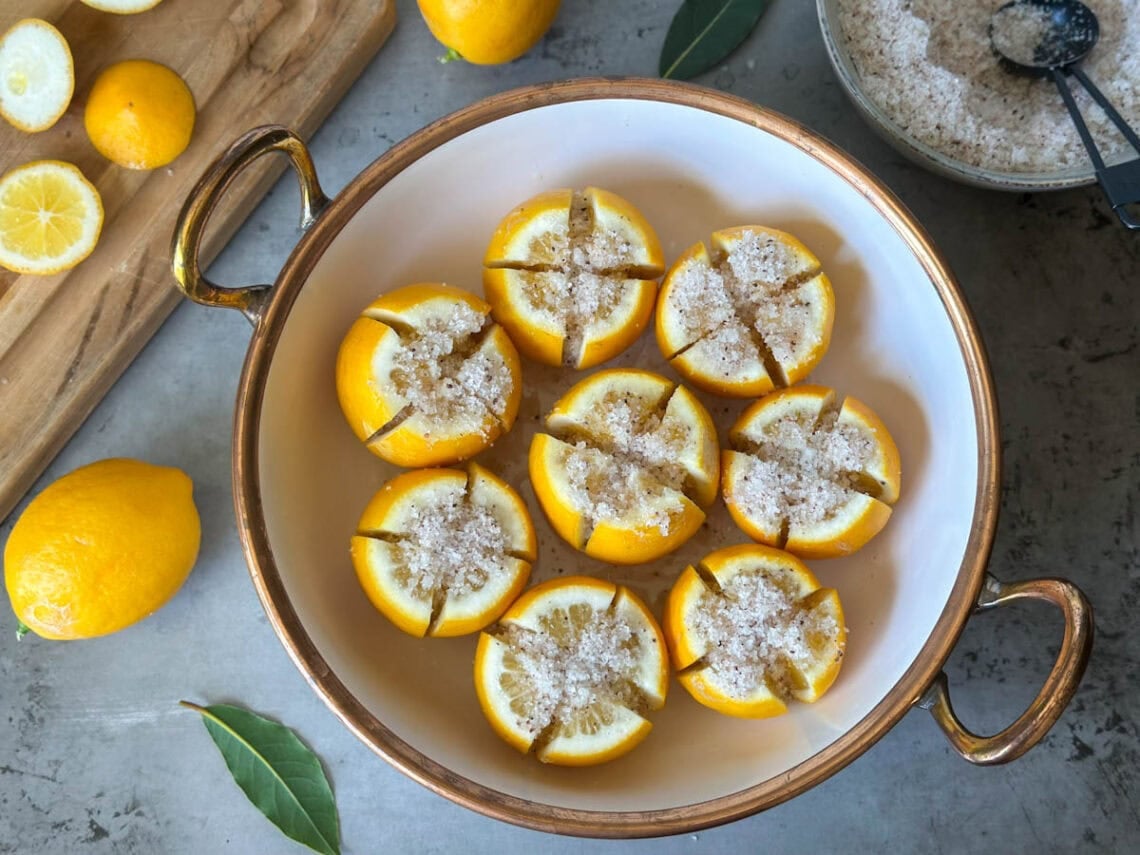 A large bowl with salt preserved lemons inside, each lemon is quartered and packed with salt.