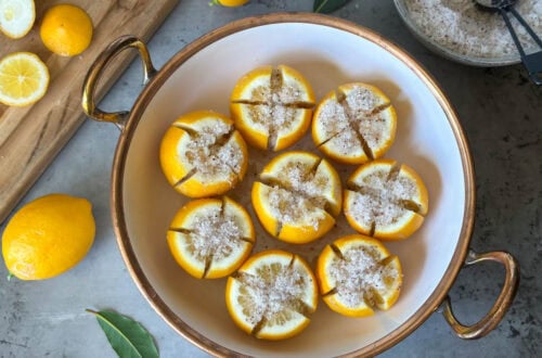 A large bowl with salt preserved lemons inside, each lemon is quartered and packed with salt.