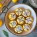 A large bowl with salt preserved lemons inside, each lemon is quartered and packed with salt.