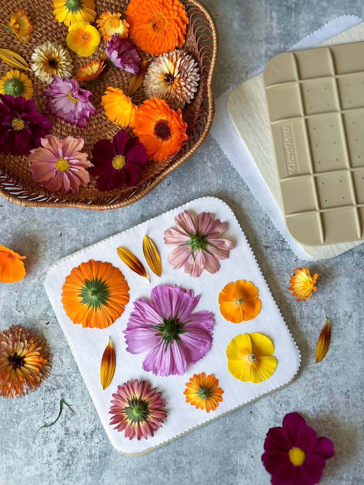Fresh blooms are arranged on a board while a wicker basket with more blooms sits nearby. 