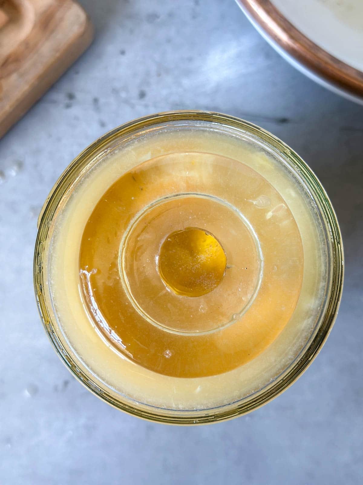 A glass ferment weight sits atop a jar full of citrus and their juices.