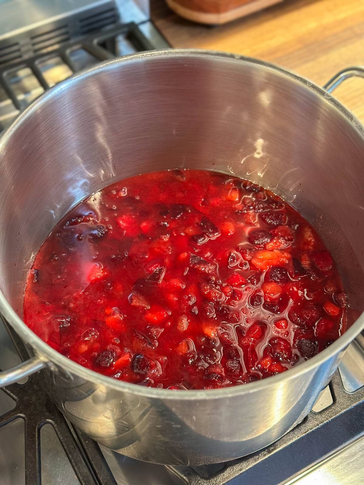A stock pot full of macerated fruit sits atop a stove.
