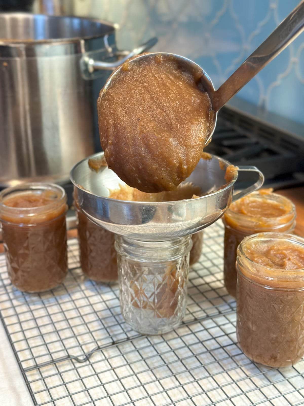 Apple butter is ladled into half pint jars via a canning funnel.