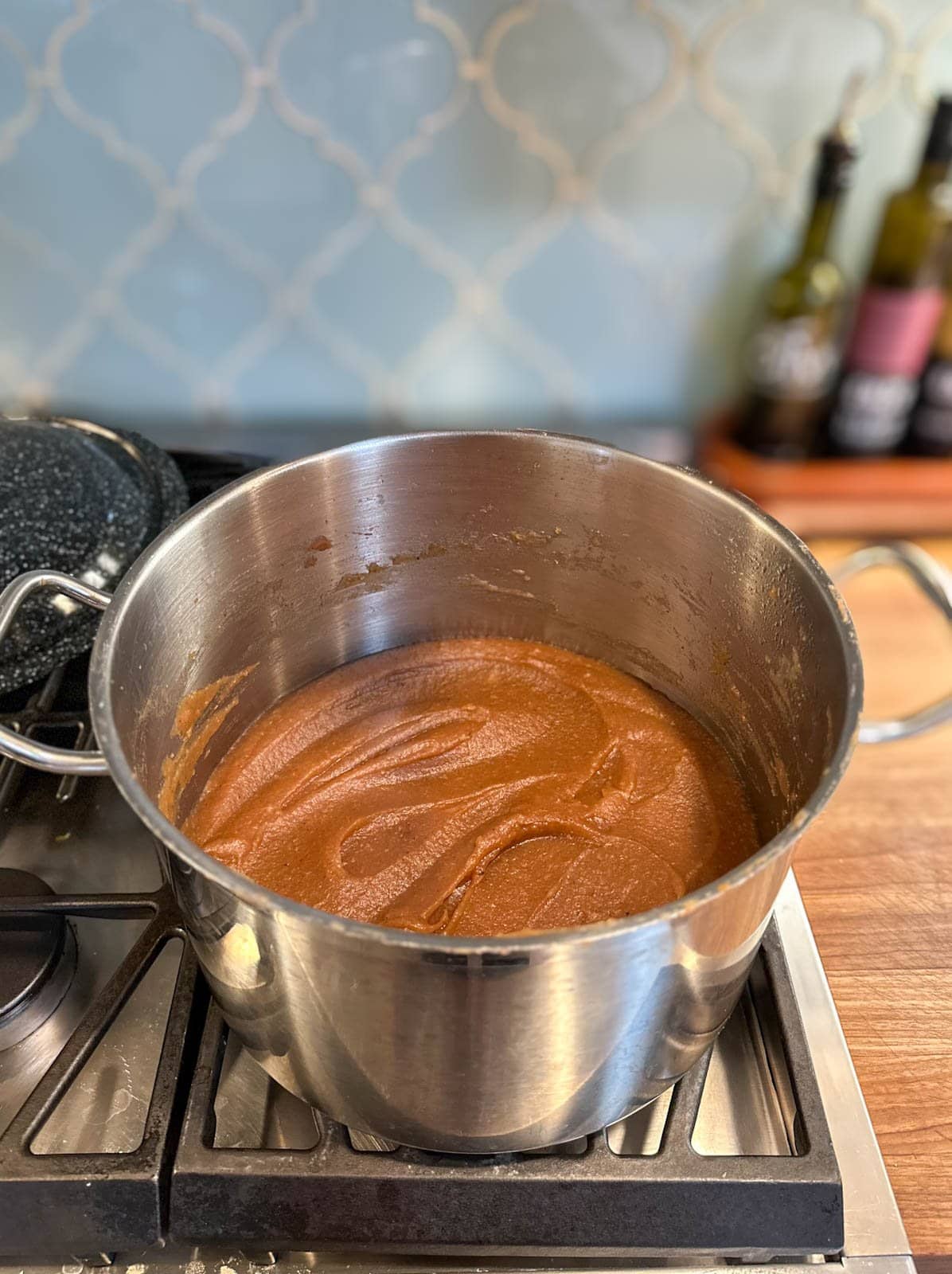 Apple butter inside of a large stock pot after it has reduced and finished cooking. It is thick and a brown caramel color.