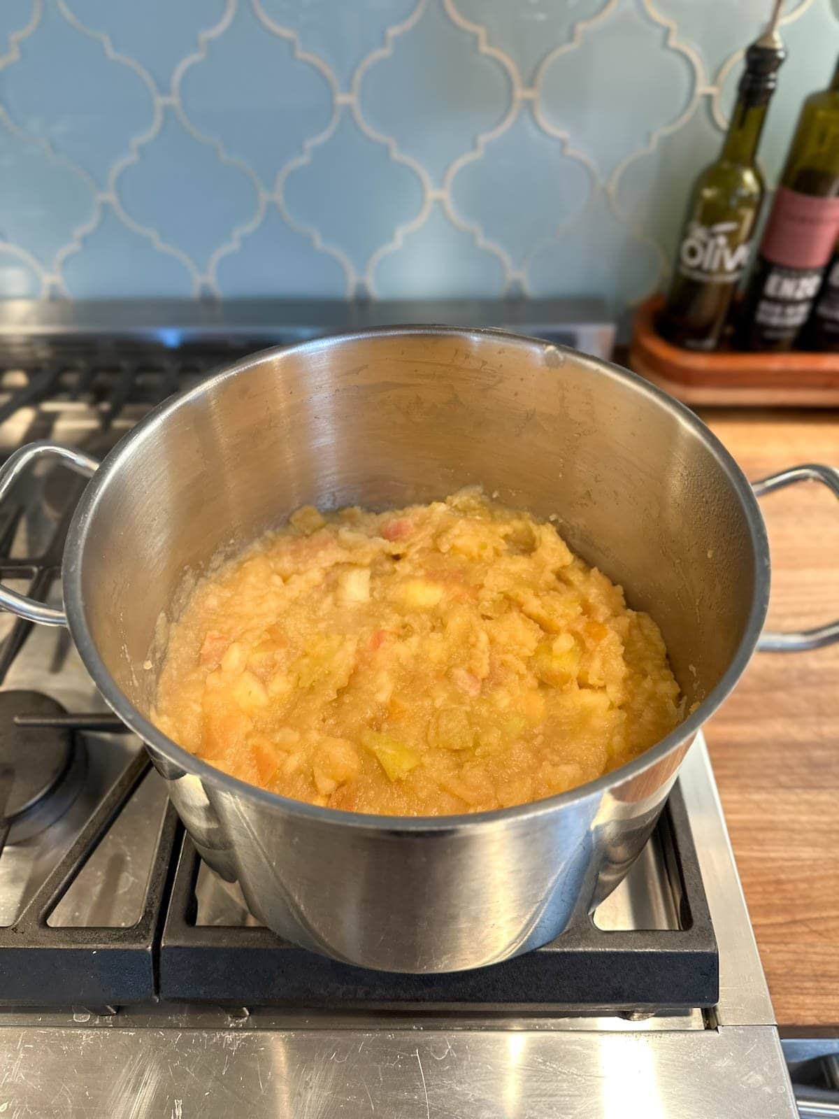 Apple pieces turn into an applesauce texture inside of a large stock pot on the stove.