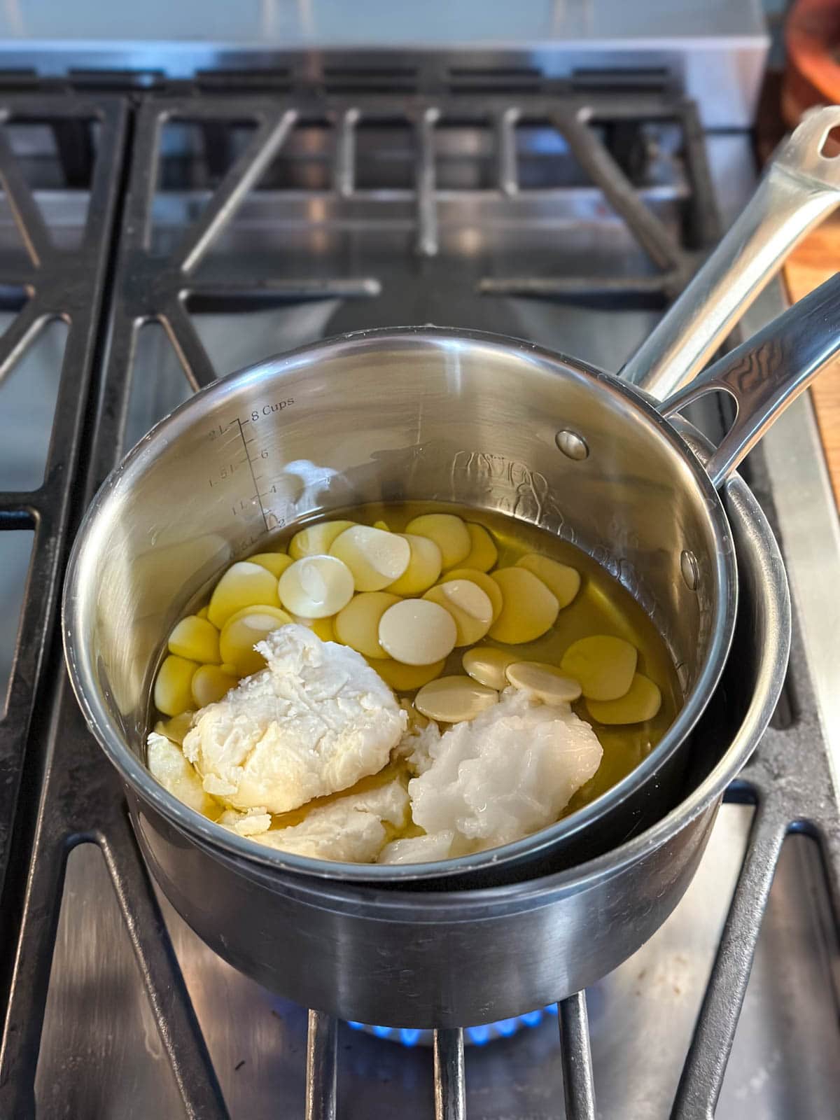 A double boiler on a stovetop (two pots nesting inside one another) full of the raw ingredients, not yet melted