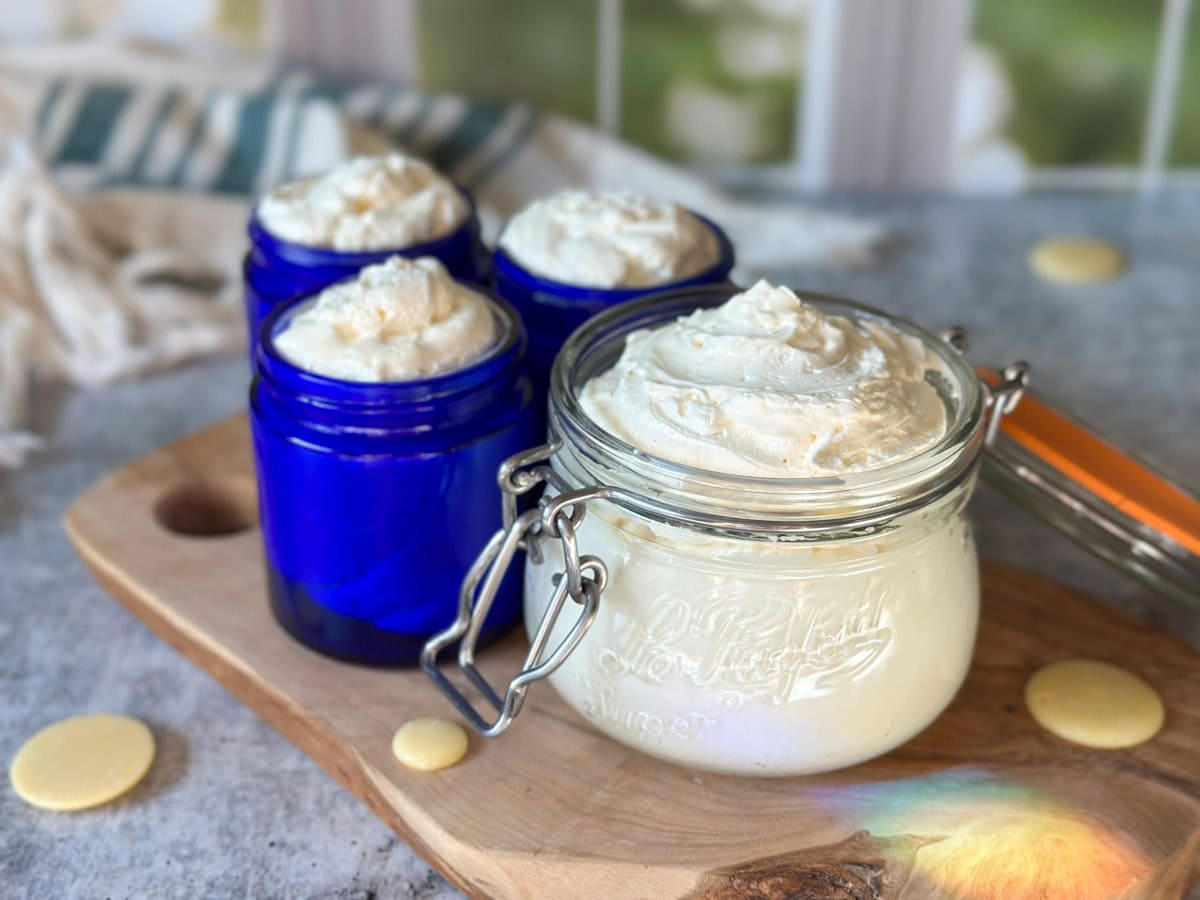 Four glass jars ranging from 4 to 12 ounces are full of creamy white whipped body butter, overfilled and a pretty swirl pattern on top like icing