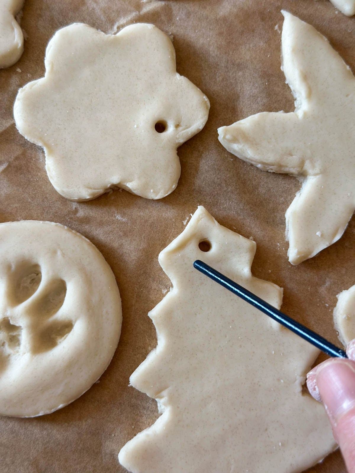 The end of a paint brush being used to make a hole at an edge of each ornament.