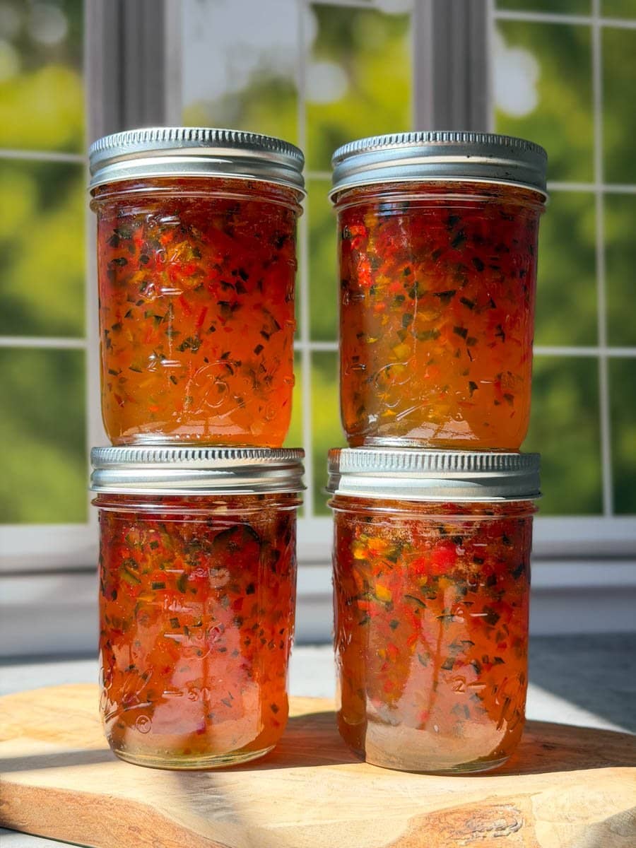 Four half pint jars of pepper jelly stacked on top of each other in two rows.